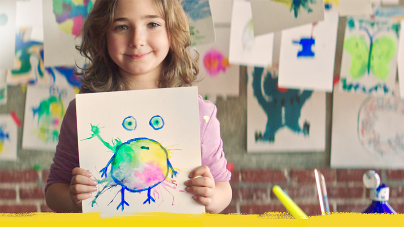 Liten flicka visar hennes teckning. Med akvarell har hon målat en bild av sin cancer