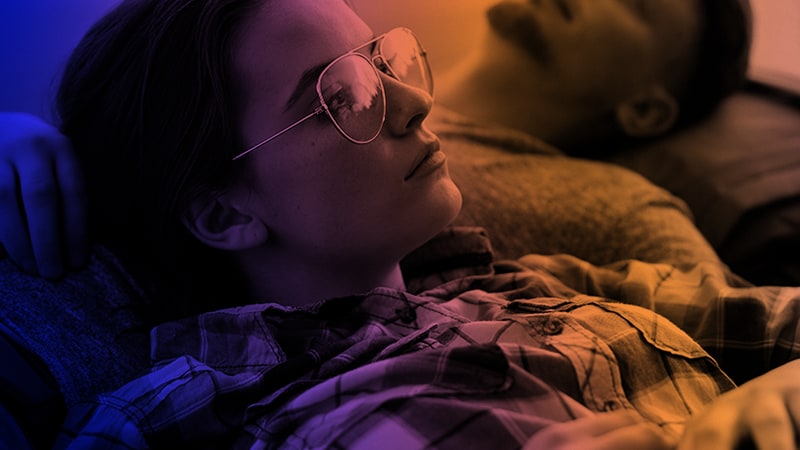 ung kvinna med glasögon som ligger i sängen